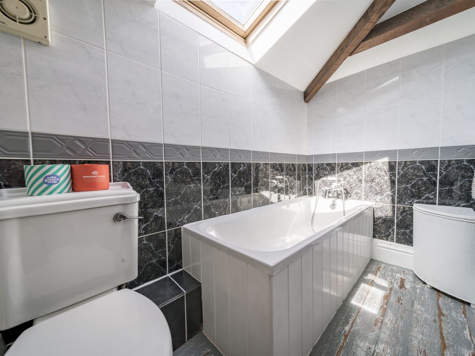 A bathroom with a bathtub and toilet at Coach House in Llangrannog