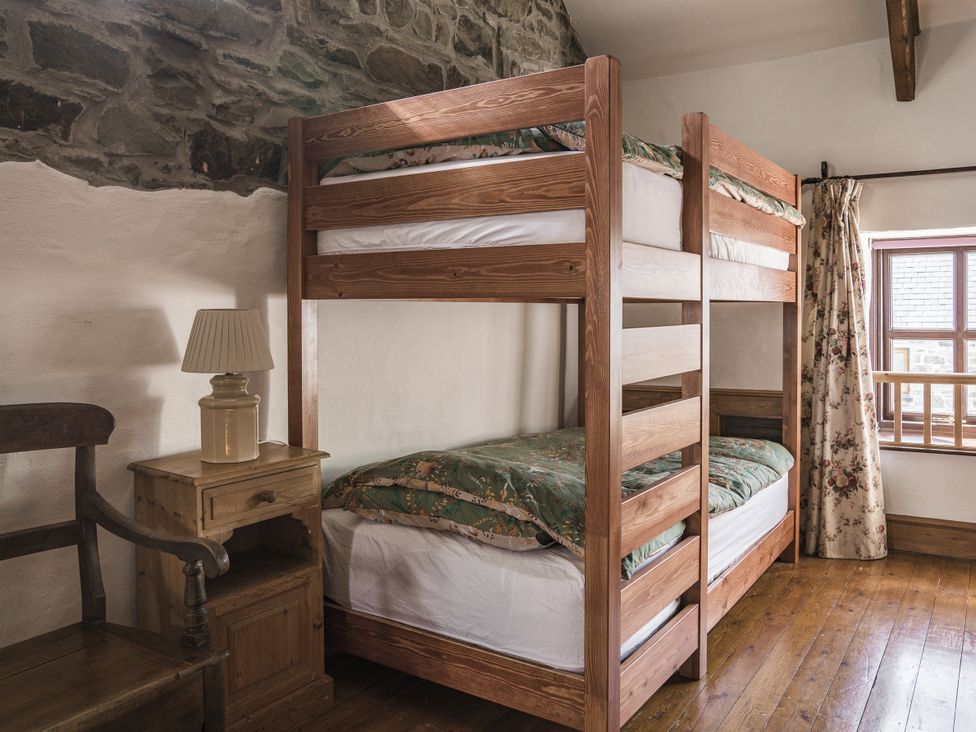 A bedroom with a bunk bed and a nightstand at Coach House in Llangrannog