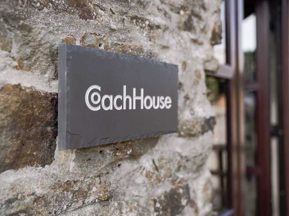 A sign with Coach House on a stone wall at Coach House in Llangrannog