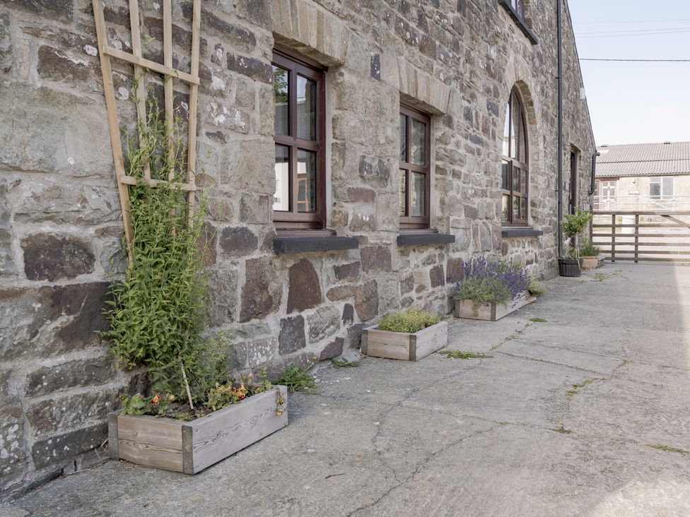 An outdoor area with stone wall and planters at Coach House in Llangrannog