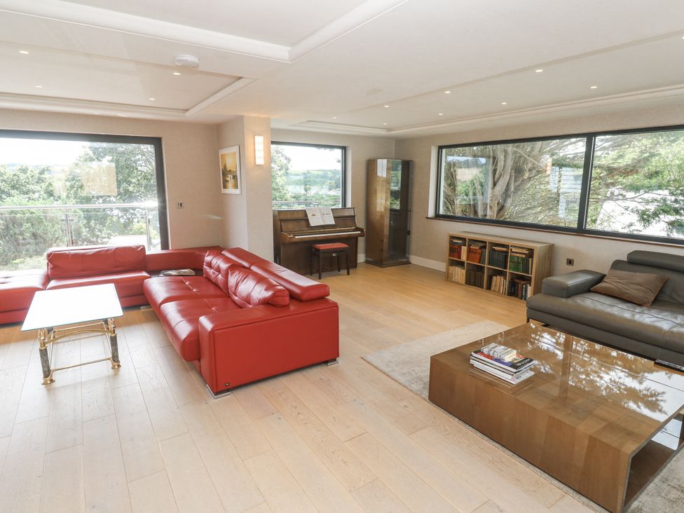 A living room with a red sofa and a piano at Treliance in Truro