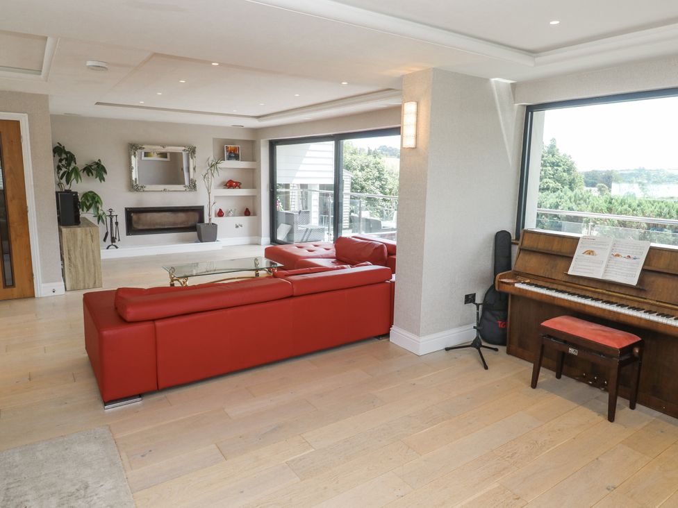 A living room with a red sofa and a piano at Treliance in Truro