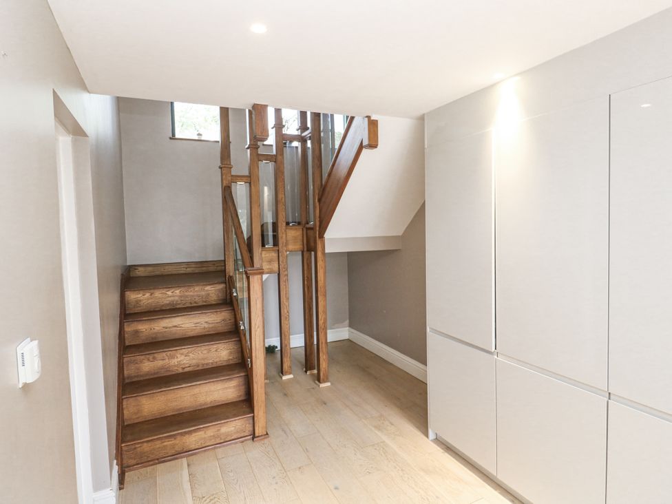 A hallway with a staircase and storage cabinet at Treliance in Truro