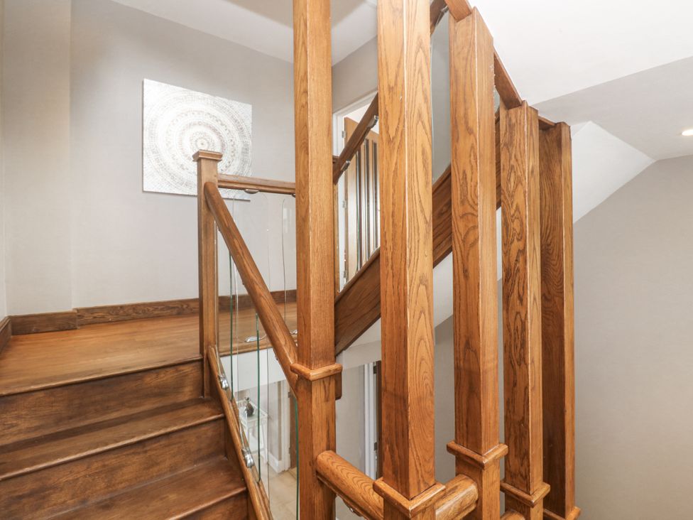 A staircase with wooden railing and artwork at Treliance in Truro