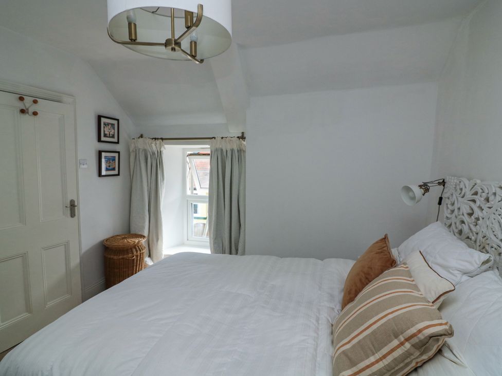 A bedroom with a bed with striped pillows a window with curtains a wicker basket and a ceiling light at Joymead in Malborough