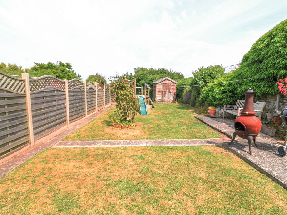 A backyard with a lawn shed climbing frame and red chiminea at Joymead in Malborough
