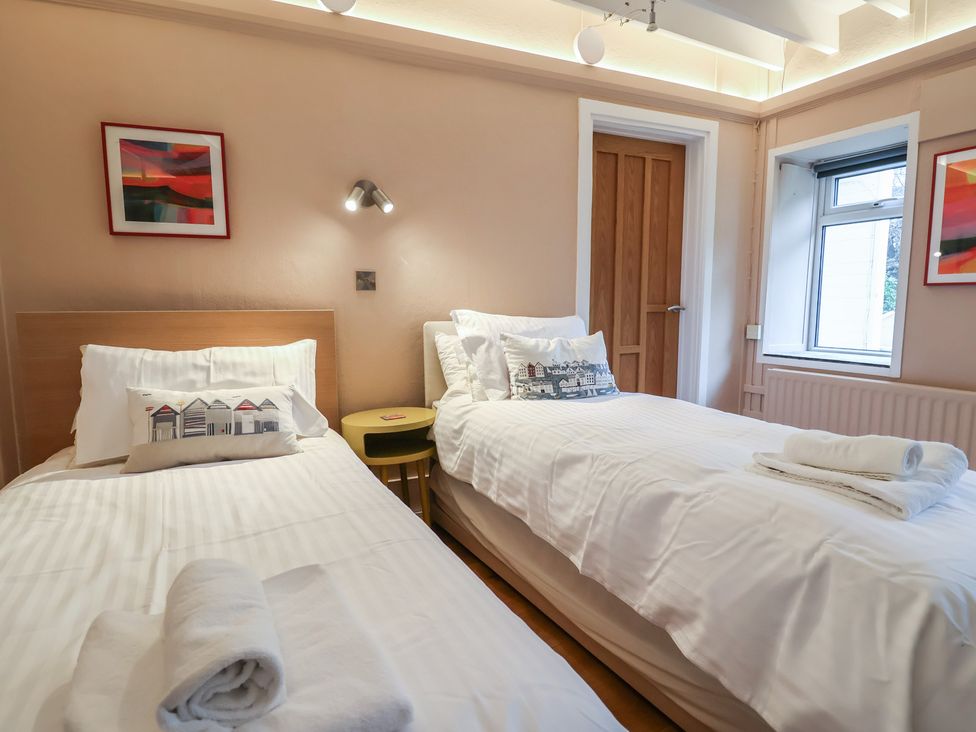 A bedroom with two single beds and a window at The Well House in Lyme Regis