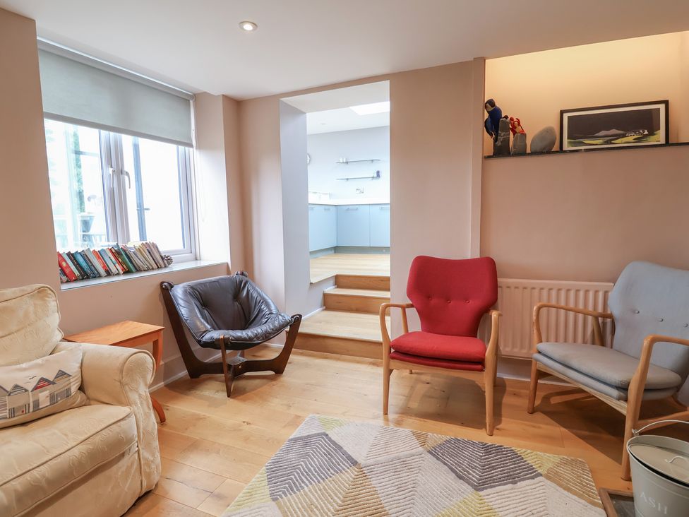 A living room with seating and a view to the kitchen area at The Well House in Lyme Regis