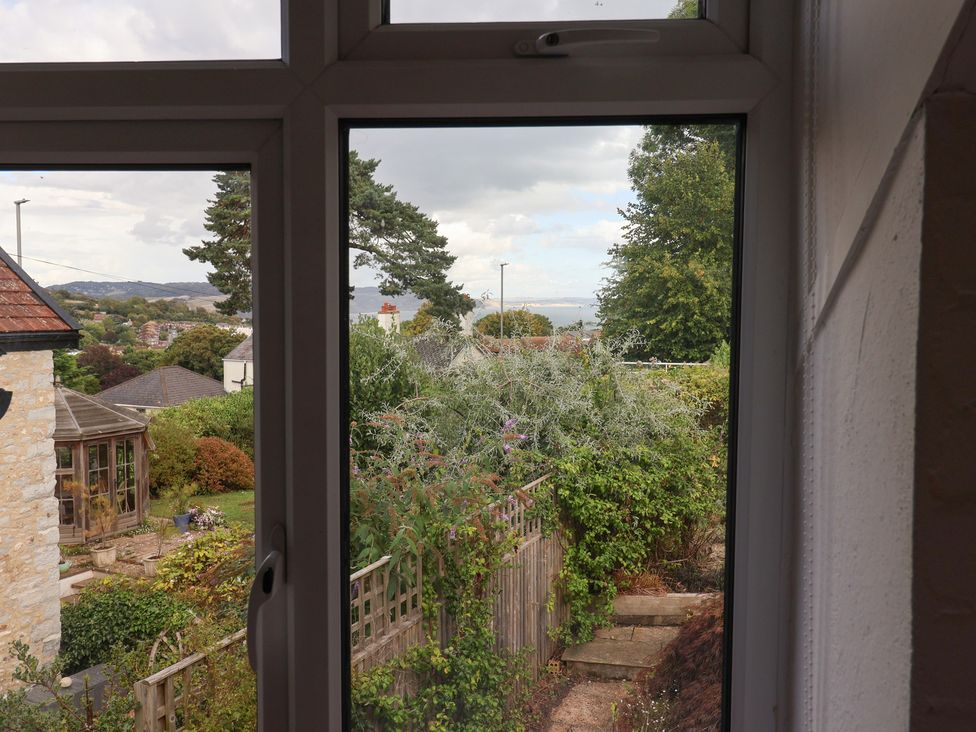 A view from a window showing a garden and trees at The Well House in Lyme Regis