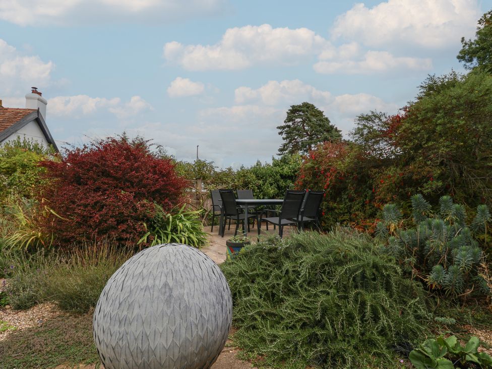 A garden with a dining set and a round sculpture at The Well House in Lyme Regis