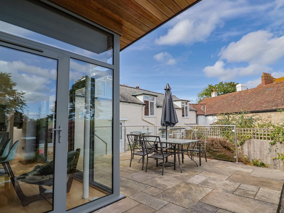An outdoor patio with a table and chairs at The Well House in Lyme Regis