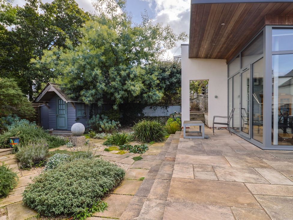 A garden with a patio, table, chair, and a shed at The Well House in Lyme Regis