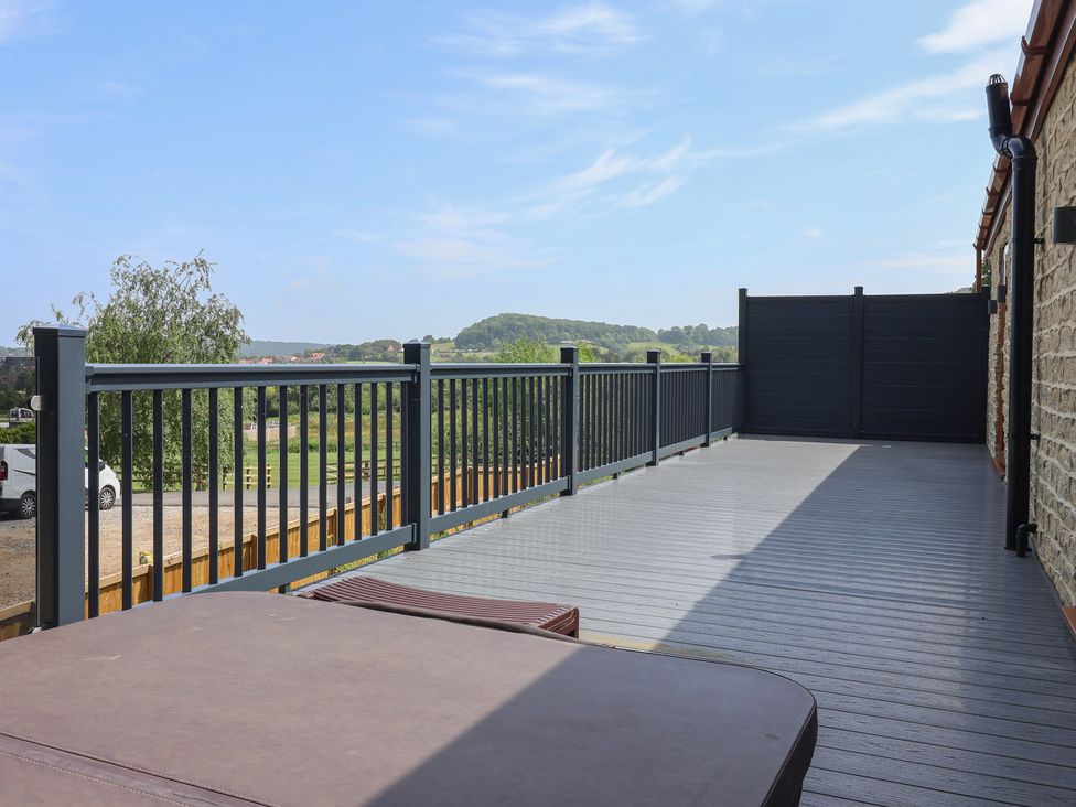 An outdoor deck with a hot tub and railing at Castle View in Scarborough