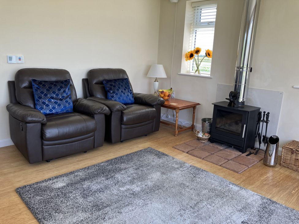A living room with recliner chairs and a wood stove at Seadrift near Stalham