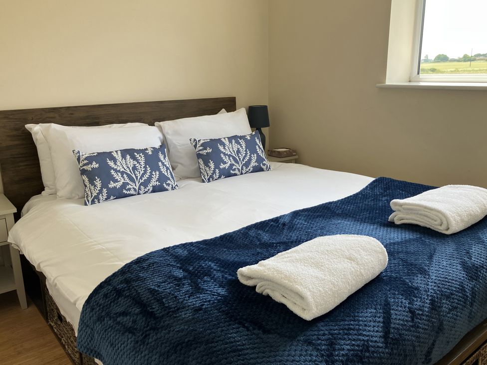 A bedroom with a double bed and decorative pillows at Seadrift near Stalham