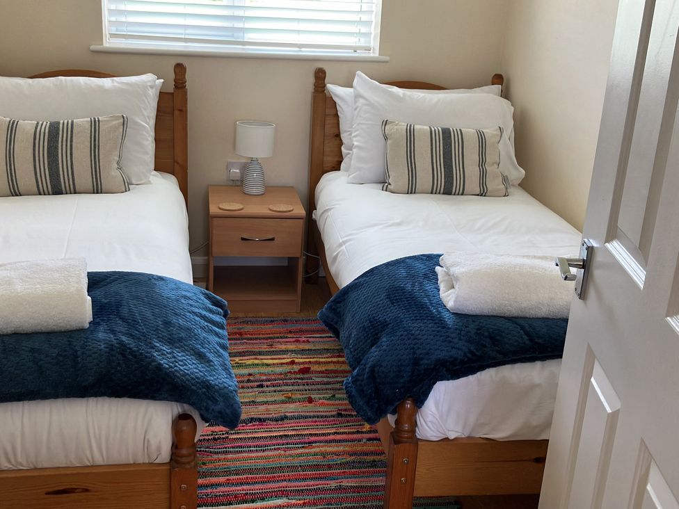 A bedroom with two single beds and a bedside table at Seadrift near Stalham