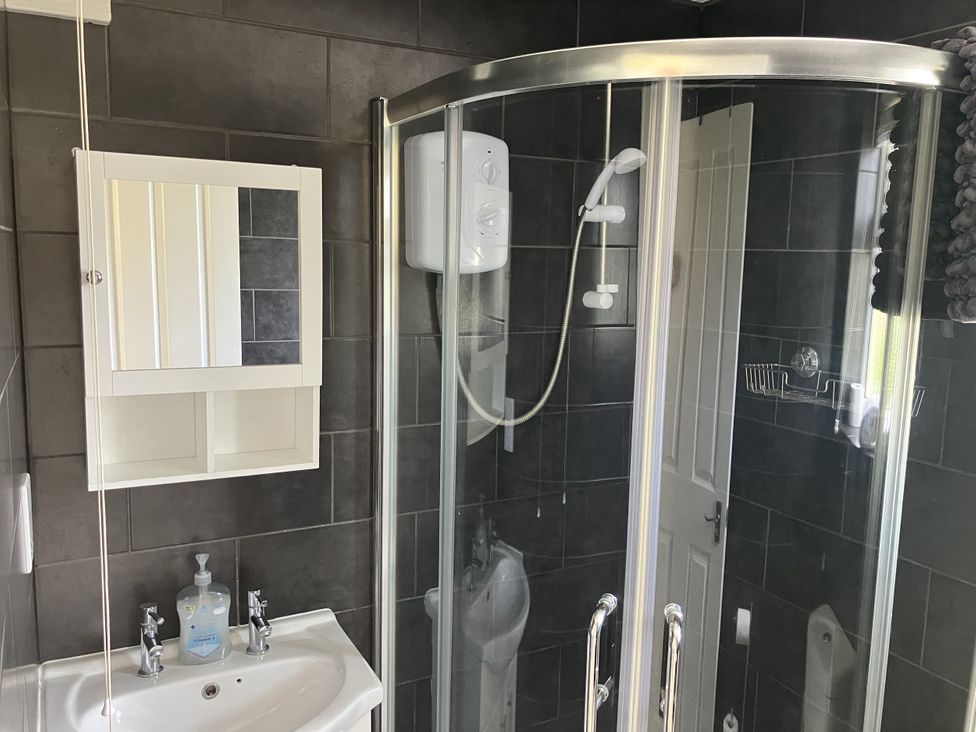 A bathroom with a shower, sink, and mirror at Seadrift near Stalham