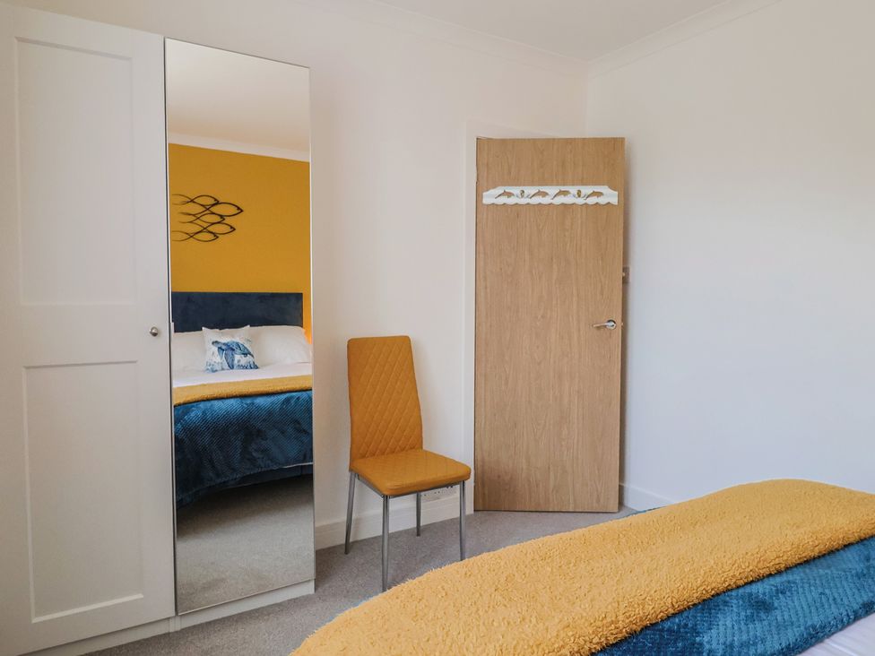 A bedroom with a mirror and a chair at 7 Cedar Drive Preston