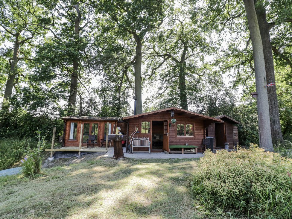 A cabin with a deck and trees in the background at The Lodge