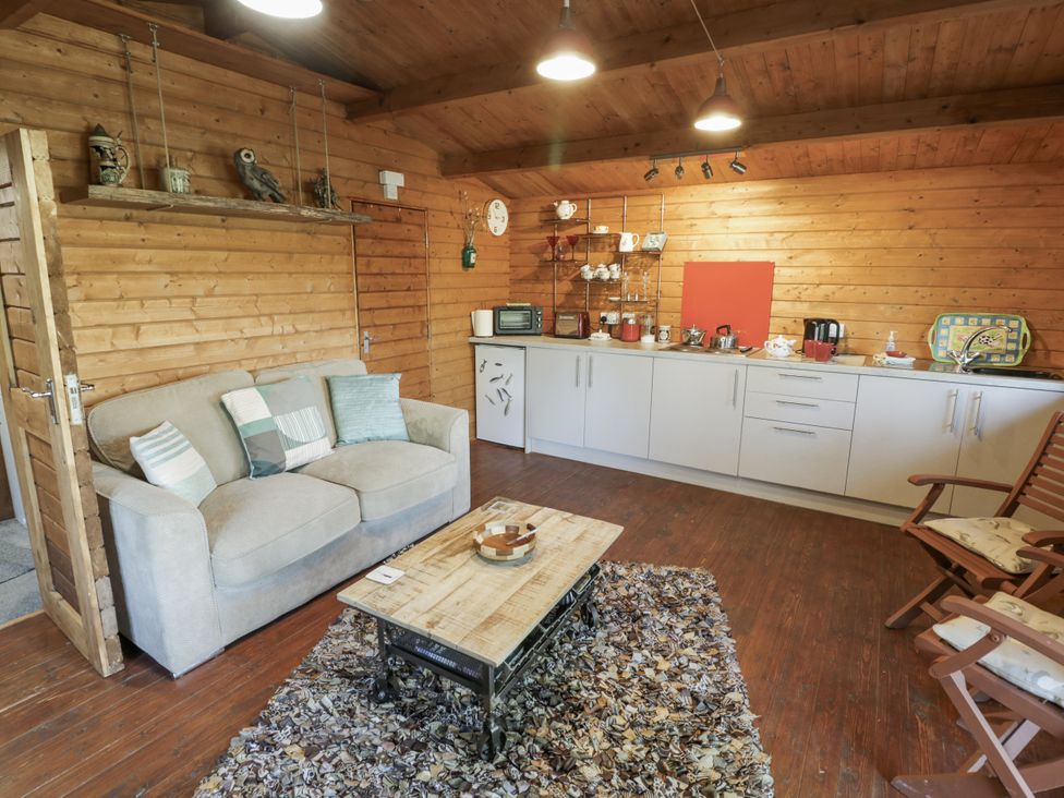 A living room with a sofa and kitchen area at The Lodge in 