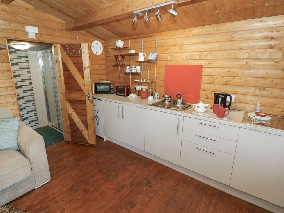 A kitchen with appliances and a door leading to a shower at The Lodge 