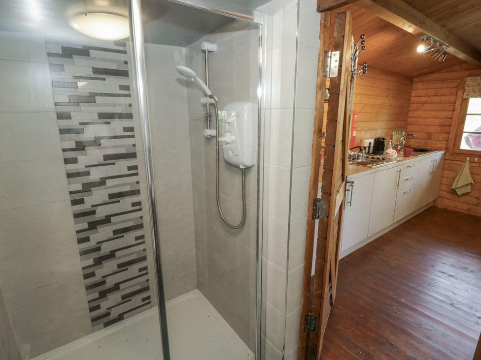A shower with a tiled wall and a kitchen area at The Lodge