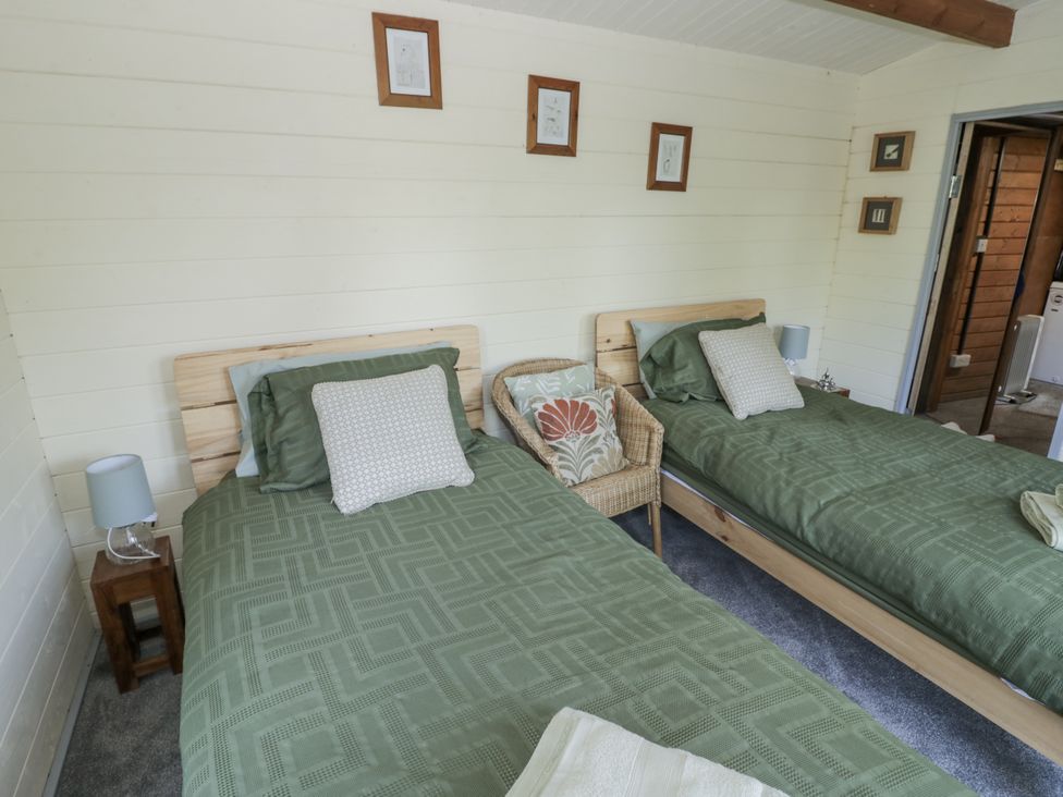 A bedroom with two beds, a bedside lamp and a chair at The Lodge in 