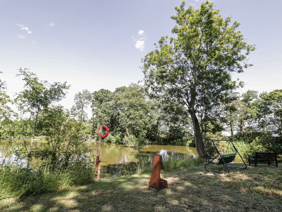 A garden with a pond, a swing and a bench at The Lodge