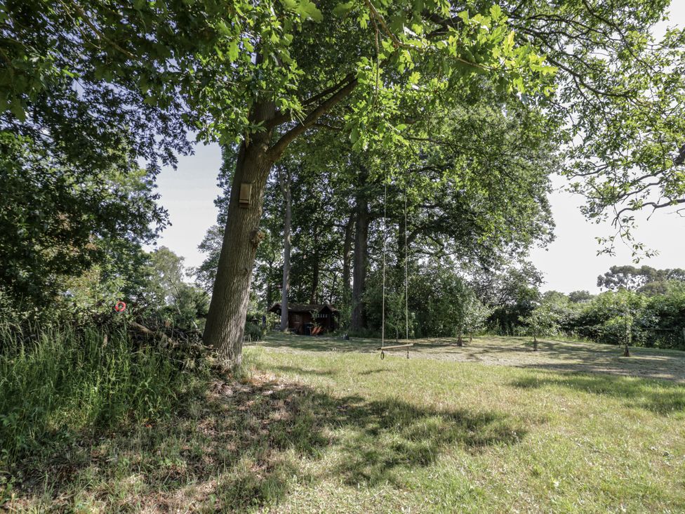 A garden with a swing and a shed at The Lodge in 