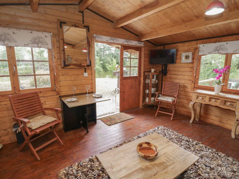 A cabin living area with chairs and a table at Carps Well Lodge Hatton near Shrewley