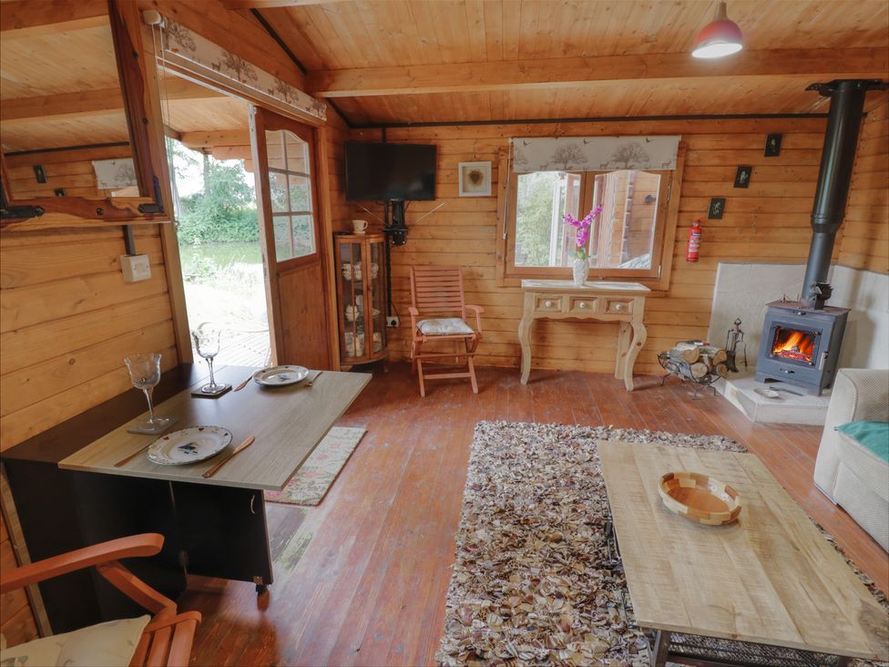 A living room with a wooden floor and stove at Carps Well Lodge Hatton near Shrewley