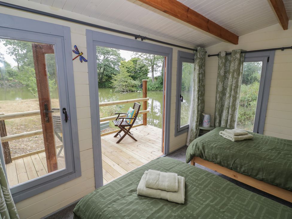 A bedroom with two beds and a view of the decking at Carps Well Lodge Hatton near Shrewley