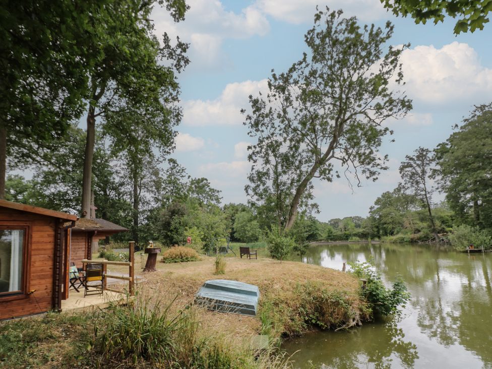 An outdoor view with wooden cabin and river at Carps Well Lodge Hatton near Shrewley