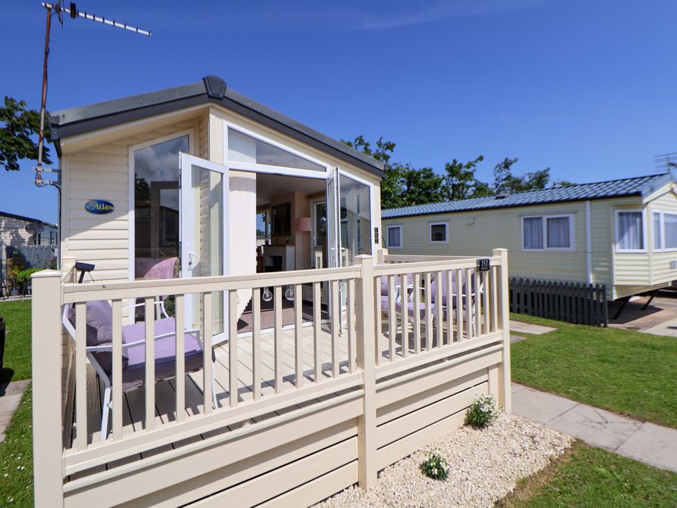 A caravan with a deck and railing at 152 Central Park in Prestatyn