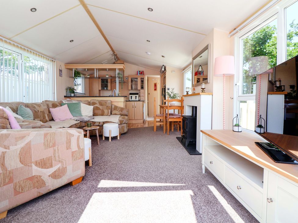 A living room with a sofa and dining area at 152 Central Park in Prestatyn