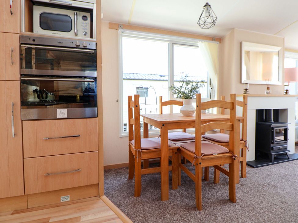 A dining room with a table and chairs at 152 Central Park in Prestatyn