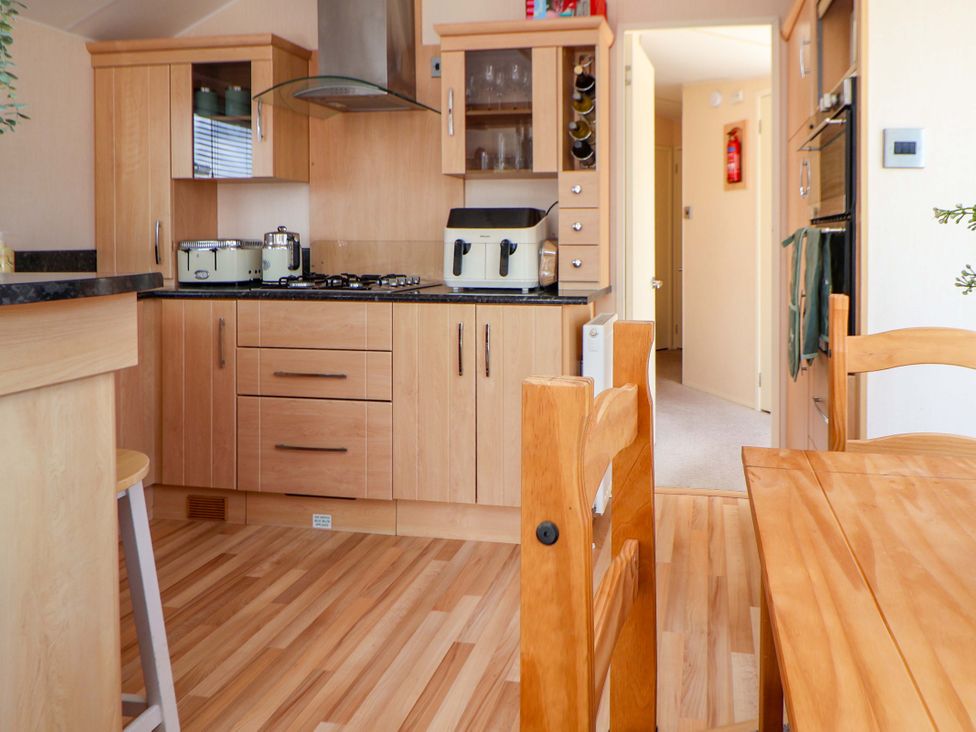 A kitchen with wooden cabinets and a dining table at 152 Central Park in Prestatyn