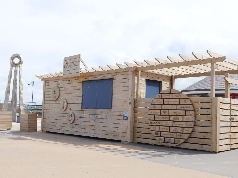 A wooden building with signage and a pergola at 152 Central Park in Prestatyn