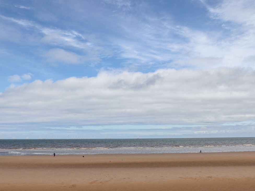 A beach with sand and ocean under a cloudy sky at 152 Central Park in Prestatyn