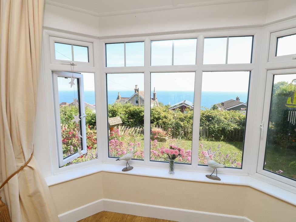 A snug with windows overlooking a garden and sea view at Poppy Cottage in Ventnor