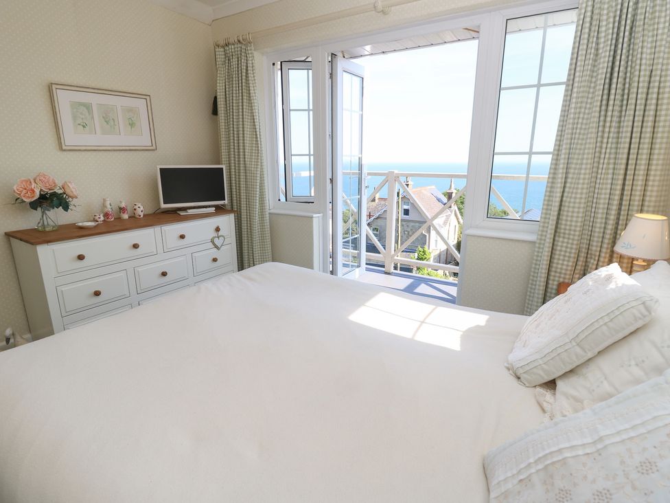 A bedroom with a bed and a view of the sea at Poppy Cottage Ventnor