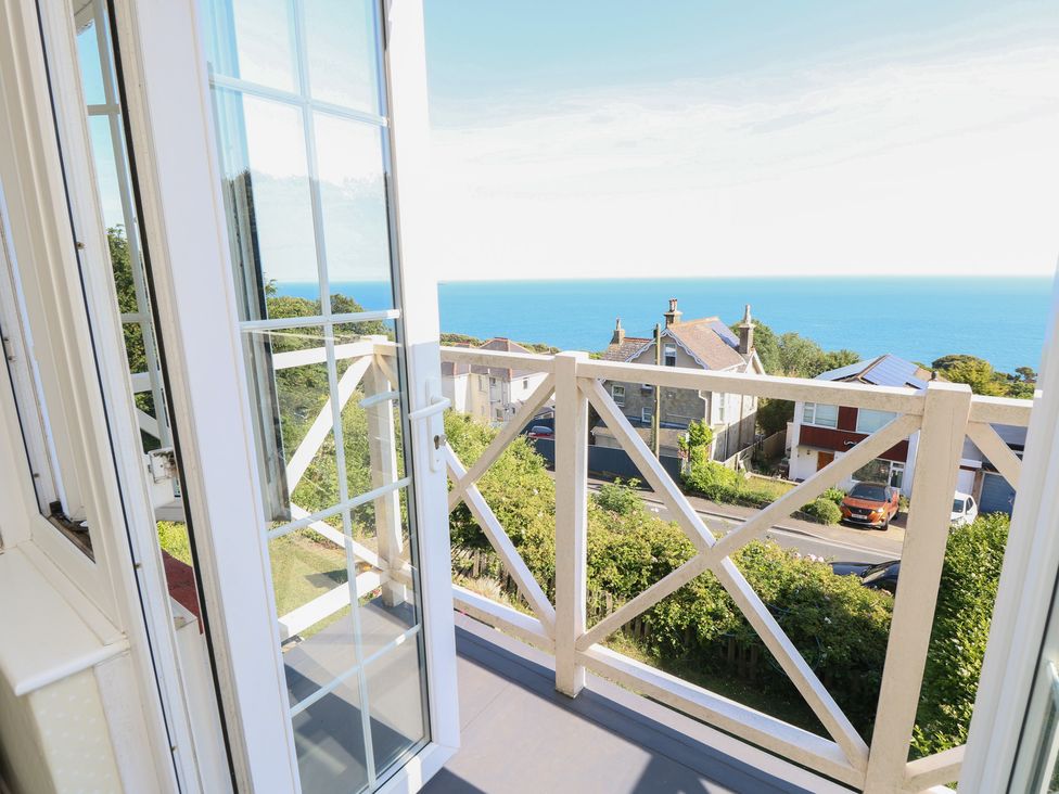 A balcony view overlooking the sea and houses at Poppy Cottage in Ventnor