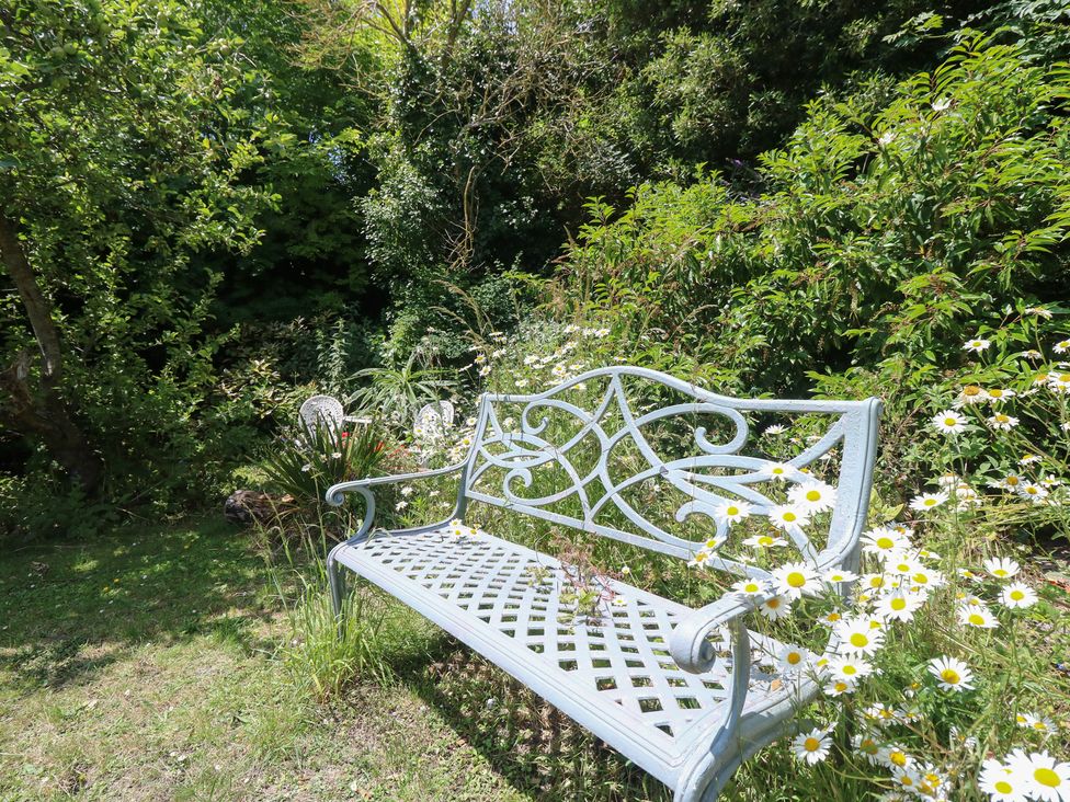 A bench surrounded by flowers in a garden at Poppy Cottage Ventnor