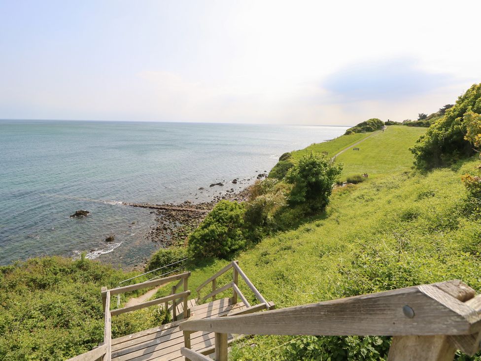A coastal view with grass and stairs leading to water at Poppy Cottage in Ventnor