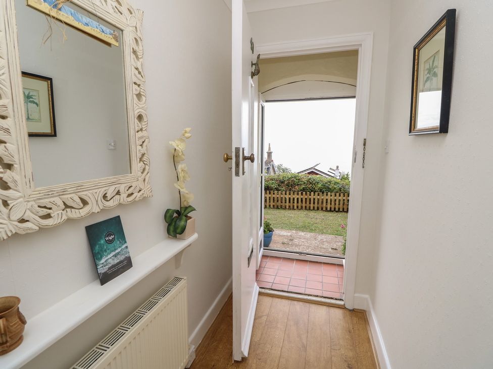 A hallway with a mirror and a view to the garden at Poppy Cottage Ventnor