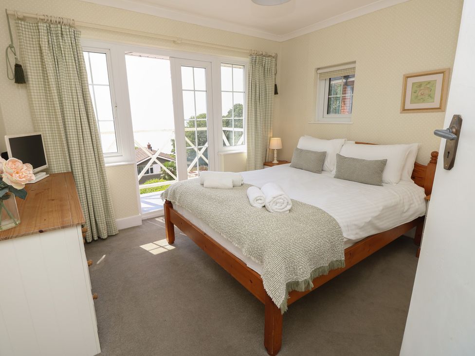 A bedroom with a bed and windows at Poppy Cottage in Ventnor