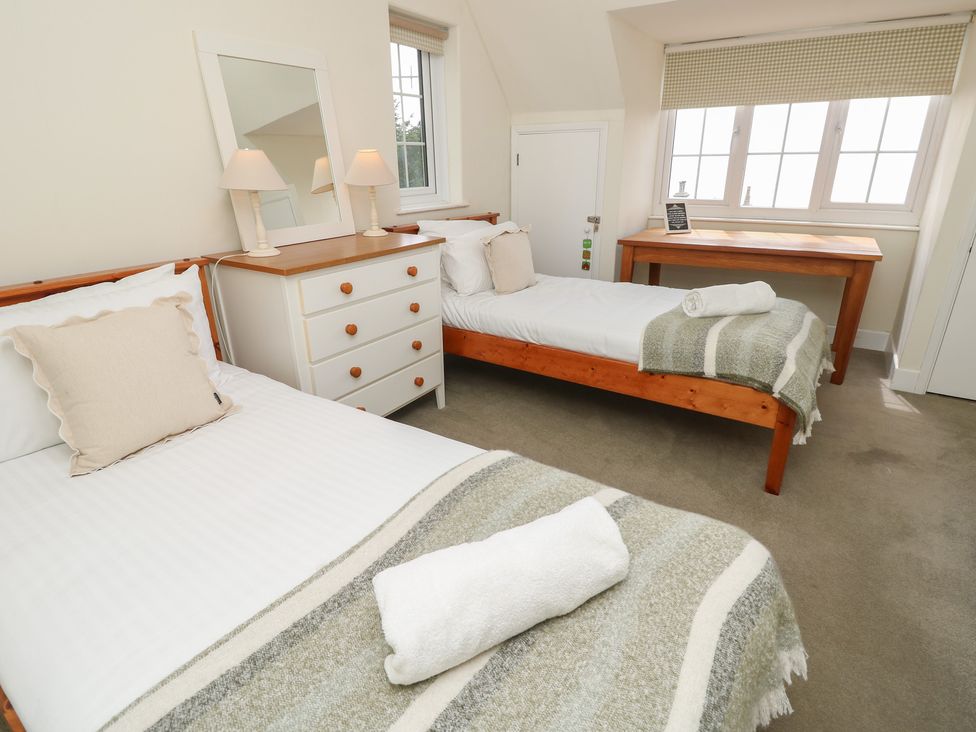 A bedroom with two beds and a table at Poppy Cottage Ventnor