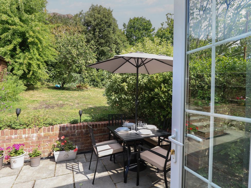 A garden with a table and chairs under an umbrella at Poppy Cottage in Ventnor