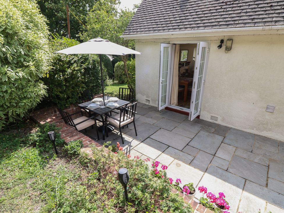 A garden with a table and chairs under an umbrella at Poppy Cottage in Ventnor