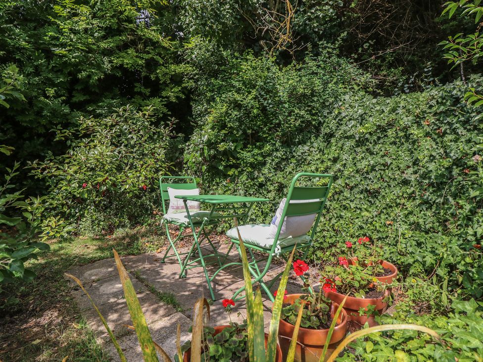 A garden with a table and chairs surrounded by plants at Poppy Cottage Ventnor